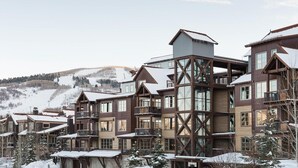 A multi-story hotel with a wooden exterior and large windows, set in a snowy mountainous area. - Silver Star 47 | Resort Amenities (Park City)
