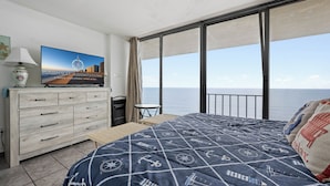 Ein Schlafzimmer mit einem großen Bett, einem Schminktisch, einem Fernseher und Meerblick.