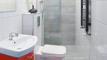 Een moderne badkamer met douche, toilet en wastafel.