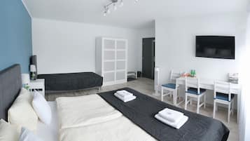 Une chambre d’hôtel moderne dotée d’un grand lit, d’un bureau avec deux chaises, d’une armoire et d’un téléviseur à écran plat fixé au mur.