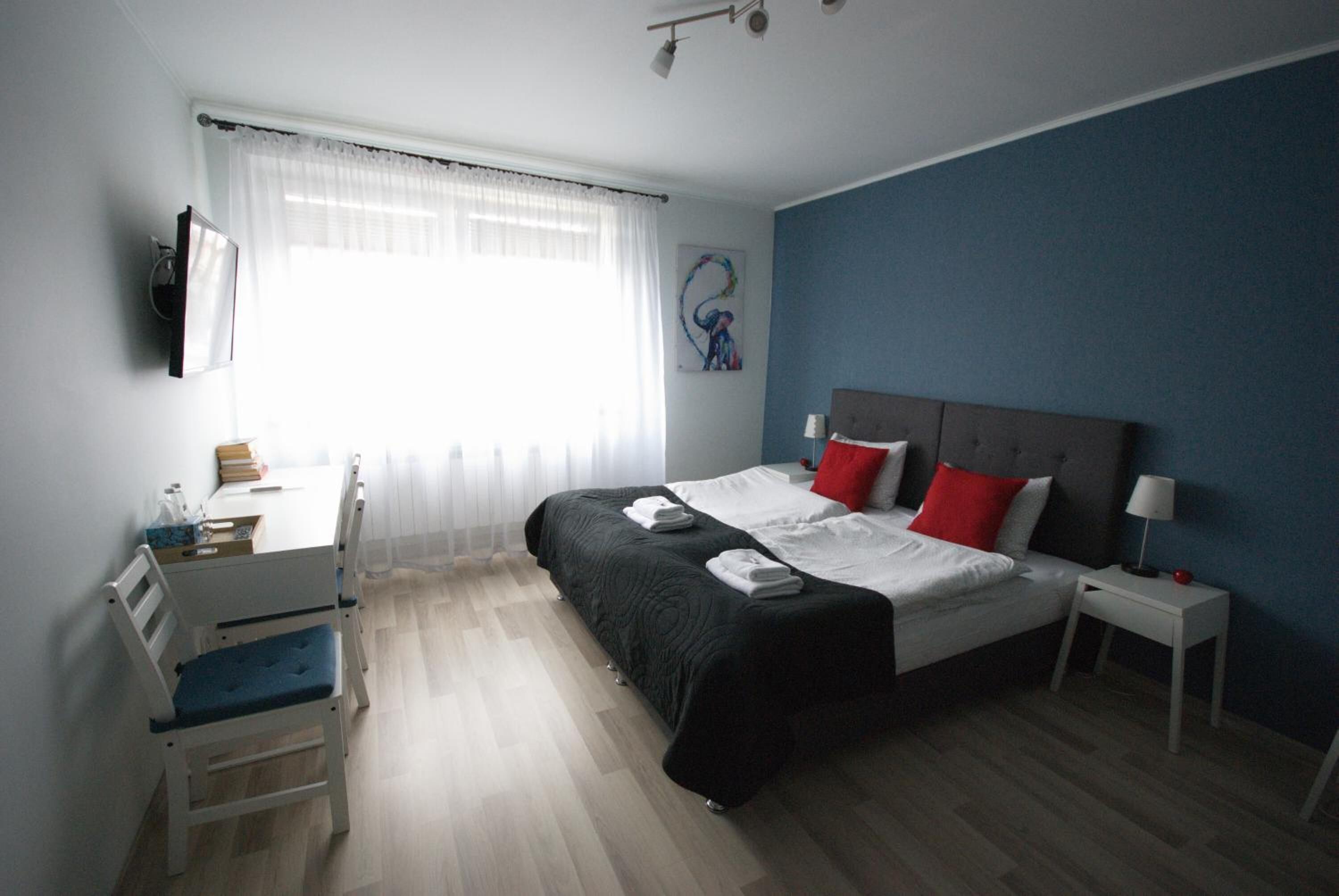 Un dormitorio con cama, mesitas de noche, un escritorio y una silla.