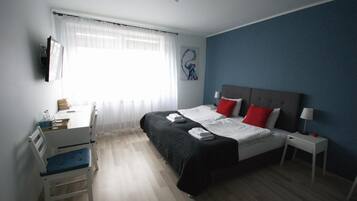 Un dormitorio con cama, mesitas de noche, un escritorio y una silla.
