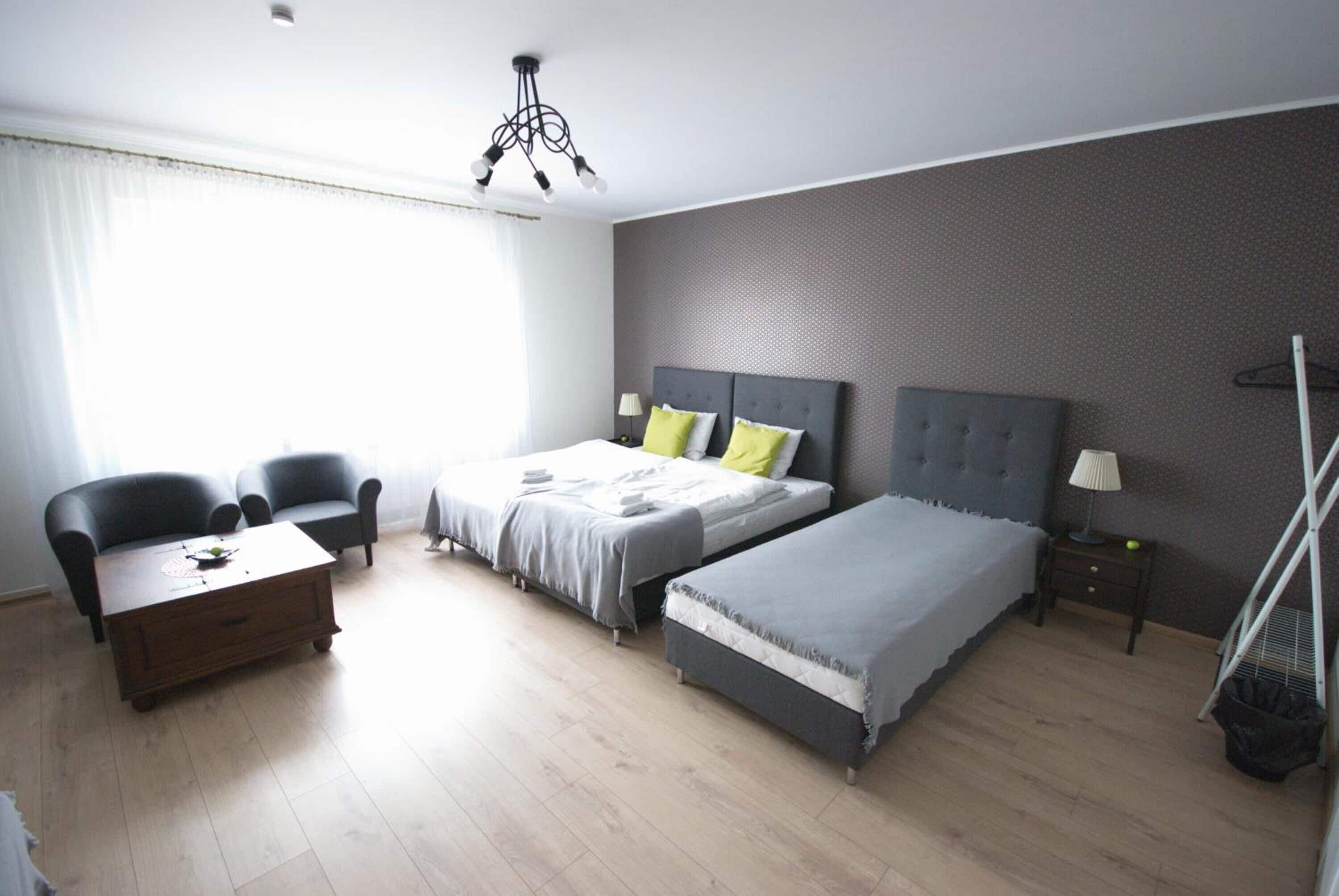 A modern bedroom with two beds, a desk, and a chair.