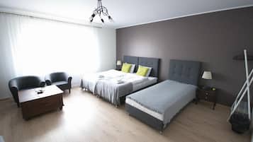 A modern bedroom with two beds, a desk, and a chair.
