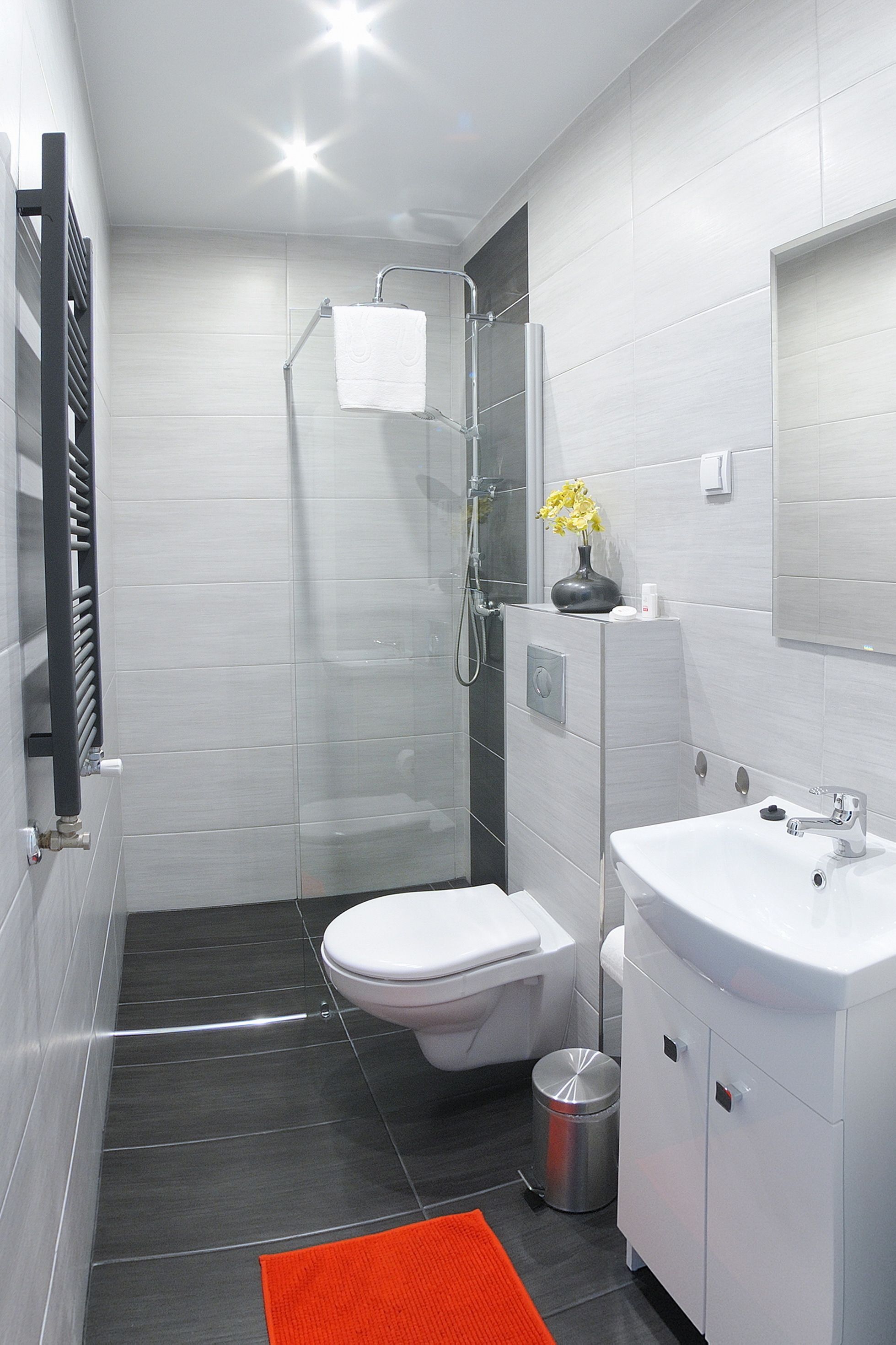 Een moderne badkamer met douche, toilet en wastafel.