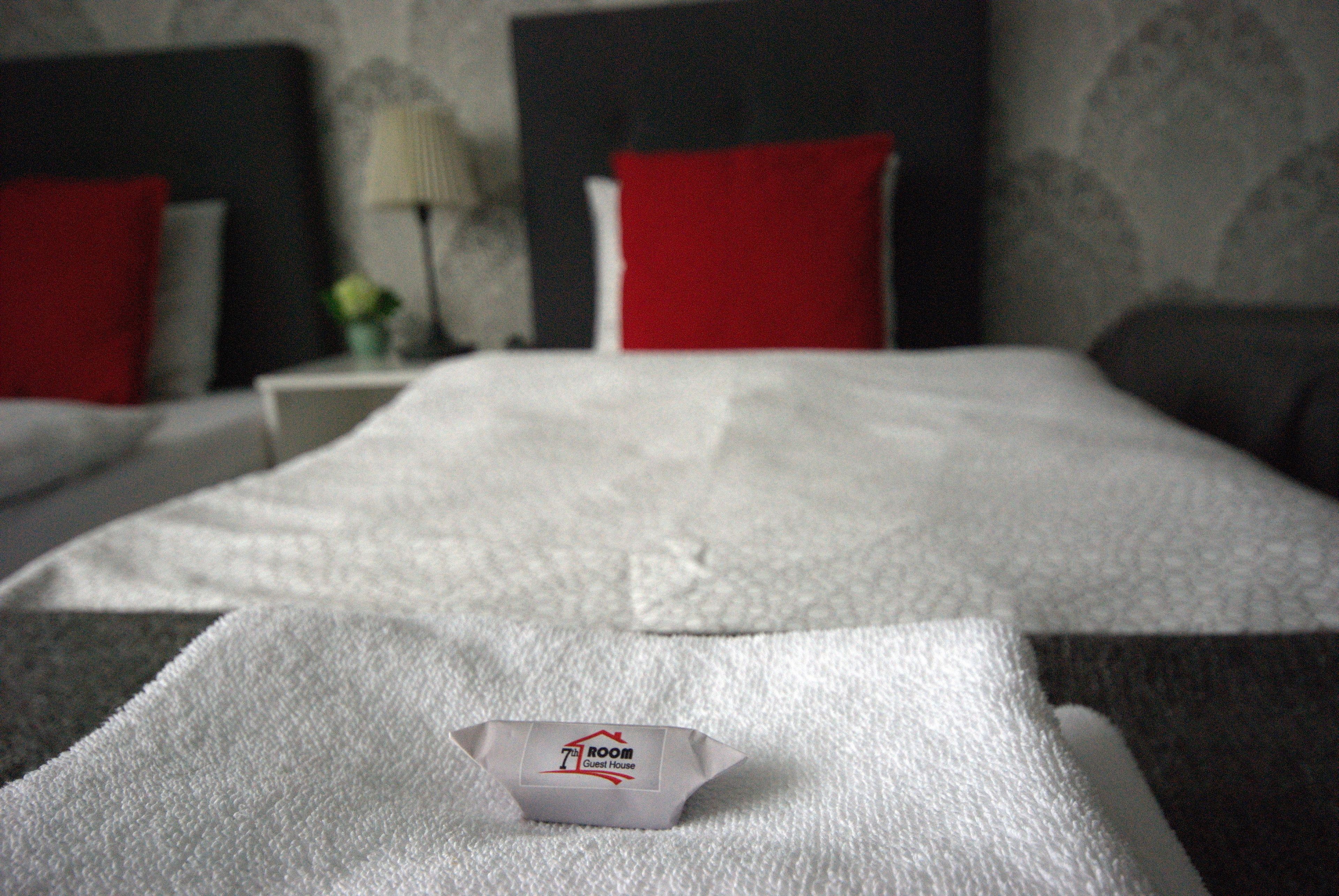 Una cama bien hecha con una colcha blanca y un pequeño objeto blanco encima.