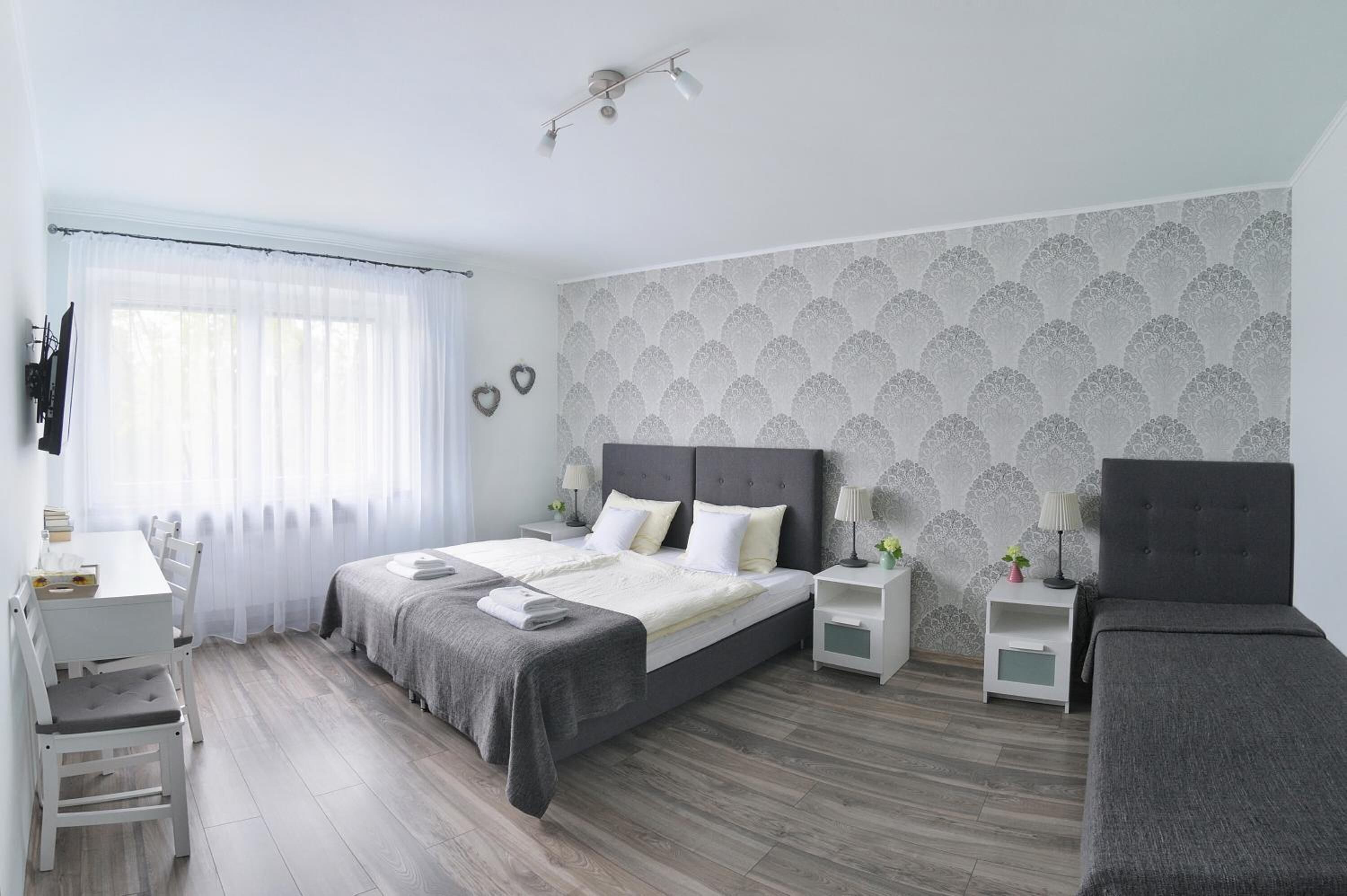 Un dormitorio moderno con una cama grande, mesitas de noche, un escritorio y una silla.