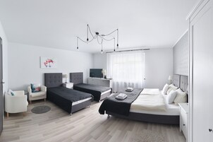 Quarto moderno com duas camas, uma televisão e uma escrivaninha.