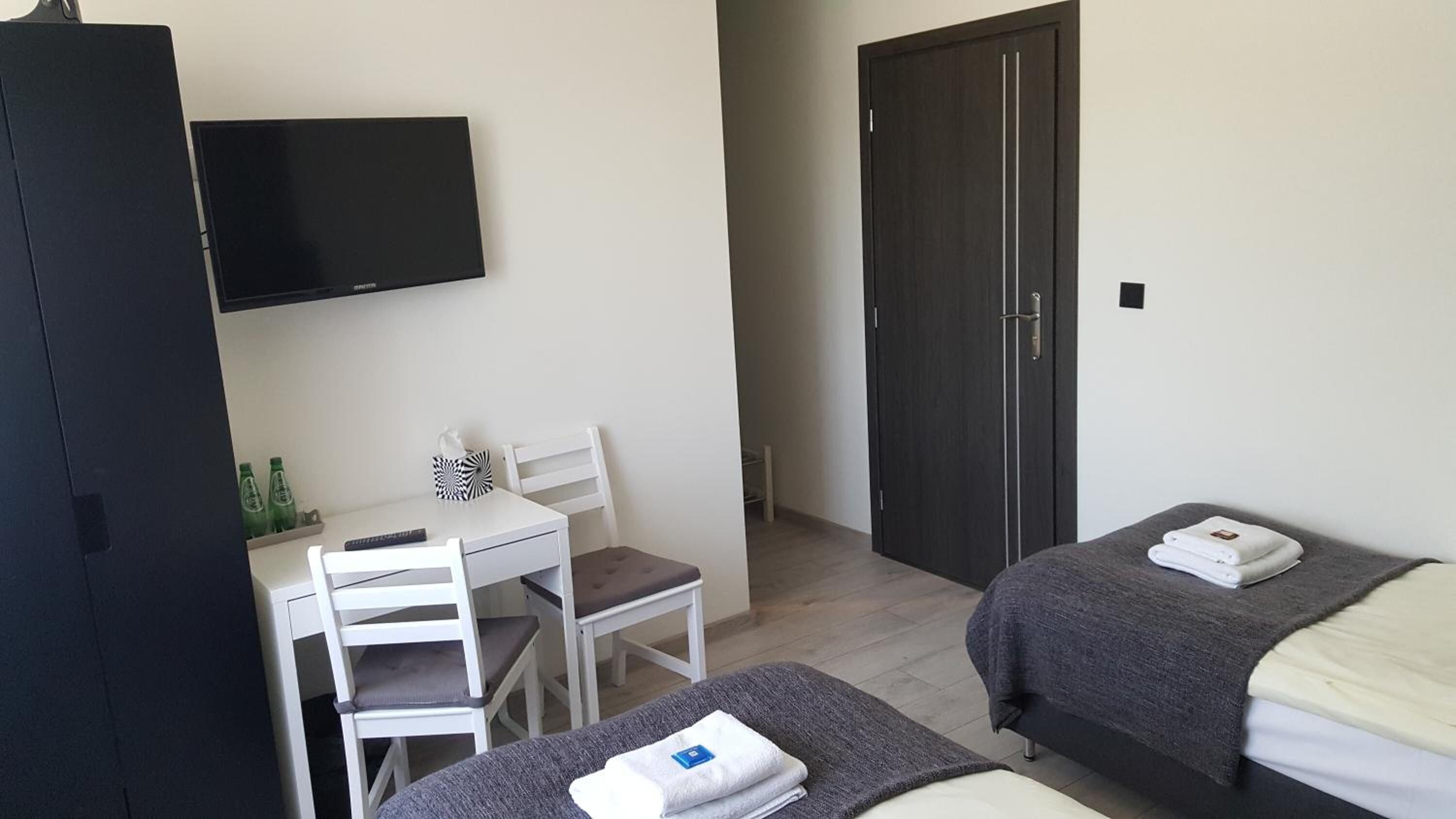 A hotel room with a desk, two single beds, a TV, and a wardrobe.