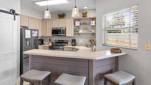 A modern kitchen with a central island, pendant lights, and a window with blinds. - Pet-Friendly 3BR | Prime Beachwalk Location (Destin)