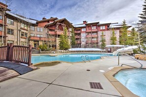 Relax by the resort pool surrounded by a wooden deck and traditional buildings.
