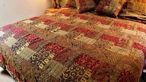 A bed with a patterned bedspread and multiple pillows.