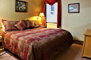 A neatly made bed with a patterned bedspread, a bedside lamp, and two framed pictures on the wall.