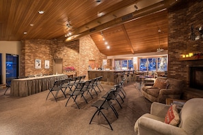 Une pièce spacieuse avec une longue table et des chaises, une cheminée et un coin bar.