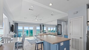 A modern kitchen with a bar area, large windows, and a view of the ocean.