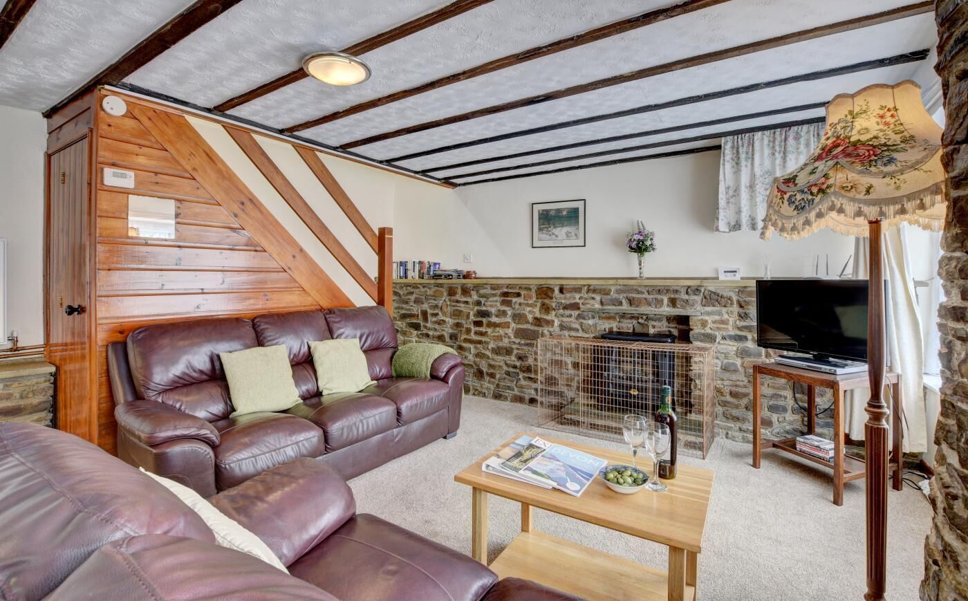 A cozy living room with a stone fireplace, leather sofa, and a television.