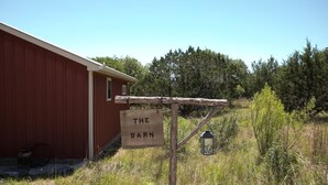 A red barn with a sign reading "THE BARN" and a lantern post. - Alamo Springs- The Barn | Relaxing Retreat (Fredricksburg)