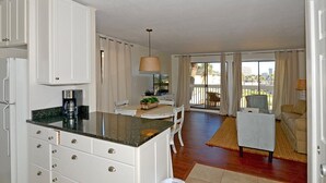 A compact kitchen with white cabinets, a coffee maker, and a dining area with a table and chairs.