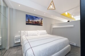 A modern bedroom with a large bed, a bedside table, a wall-mounted shelf, and a cityscape painting. - Vibrant Loft near Plateau Mont Royal and Festivals (Montréal)