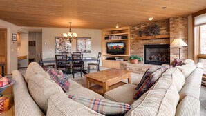 Ein gemütliches Wohnzimmer mit Holzboden, Kamin, Fernseher und Essbereich mit Stühlen und Tisch.