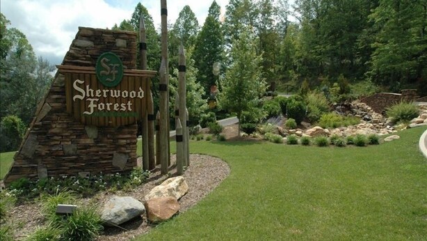 En skylt som markerar Sherwood Forest, bestående av en konstruktion i sten och trä, omgiven av en anlagd trädgård med gräs, stenar och träd.