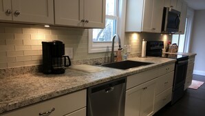 A modern kitchen with white cabinets, a granite countertop, a dishwasher, a sink, and a microwave. - SUPER UPSCALE RANCH! (Mentor)
