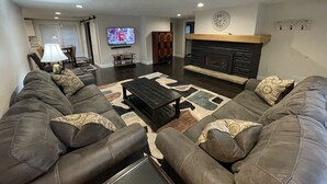 A living room with a sectional sofa, a fireplace, a television, and a dining area with chairs and a table. - SUPER UPSCALE RANCH! (Mentor)