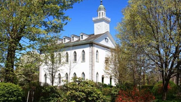 A white church with a bell tower and arched windows, surrounded by trees and greenery. - SUPER UPSCALE RANCH! (Mentor)