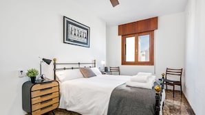 A neatly arranged bedroom with a bed, bedside tables, a desk, and a chair.