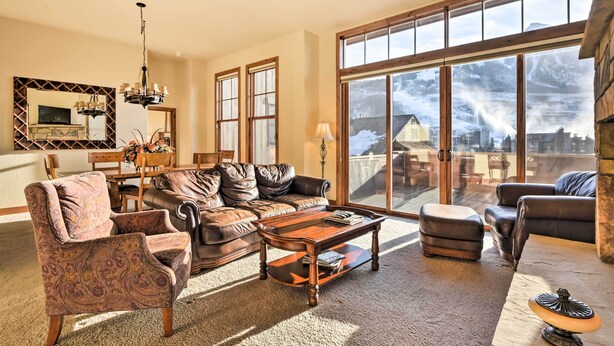 A spacious living room with a large window, a fireplace, and a cozy seating area. - Crested Butte Townhome w/ Views - Steps to Lifts! (Mt. Crested Butte)