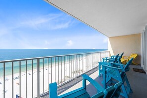 Ein Balkon mit Blick auf Strand und Meer. Blaue und gelbe Adirondack-Stühle sind aufgestellt.