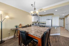 A modern kitchen with a central island, white cabinets, and a chandelier.