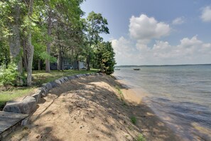 Enjoy a serene lakeside retreat surrounded by lush greenery and a sandy beach area.