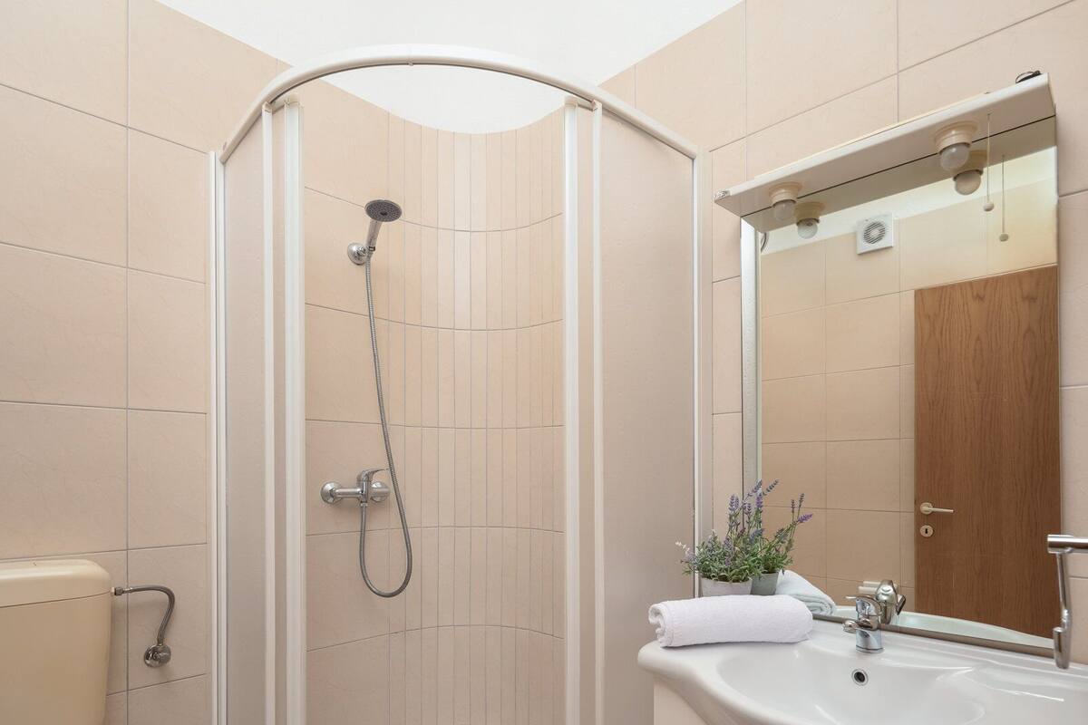 A modern bathroom with a glass-enclosed shower, a white sink, and a toilet.
