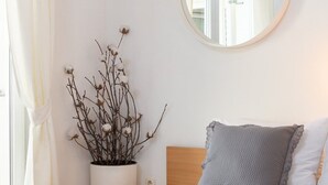 A bedroom with a bed, a round mirror, a potted plant, and a window with curtains. - Apartments Arausa with Pool (Vodice)