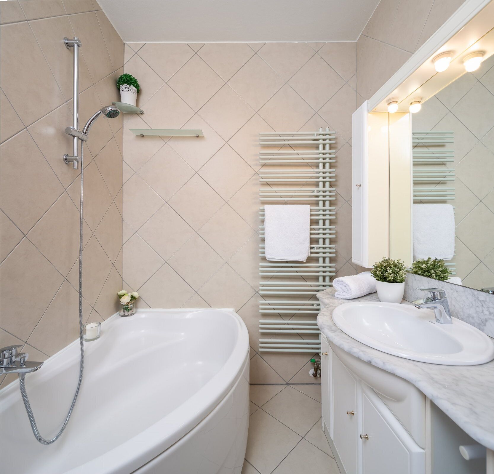 A modern bathroom with a freestanding bathtub, a wall-mounted radiator, a vanity with a sink, and a mirror.