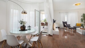 A modern living room with a glass dining table, white chairs, a grey sofa, and a black armchair. - Apartments Arausa with Pool (Vodice)