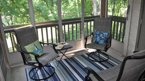 A covered porch with two chairs and a small table, large windows with a view of trees, and a striped floor mat. - GREAT LOCATION LUXURY 3 BDRM 3 BATH LAKEFRONT  HEATED INDOOR POOL STAY&PLAY GOLF (Branson)