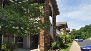 A multi-story building with a brick facade, a covered walkway, and a parking area with cars. - GREAT LOCATION LUXURY 3 BDRM 3 BATH LAKEFRONT  HEATED INDOOR POOL STAY&PLAY GOLF (Branson)