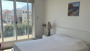 Un dormitorio con una cama, ventilador de techo, ventana y un cuadro en la pared.