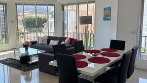 Una sala de estar moderna con comedor, ventanas amplias y ventilador de techo.