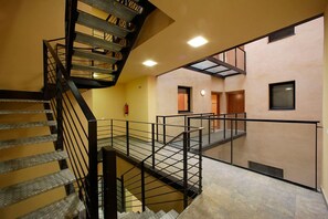 A multi-level interior with a spiral staircase, a glass balustrade, and a fire extinguisher on the wall. - Charming Old Town Flat Carders with Balcony (Barcelona)