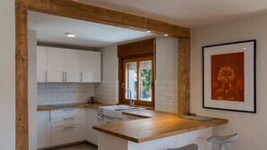 Una cocina moderna con armarios blancos, encimera de madera y una ventana con persianas.