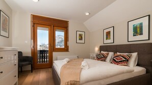 Un dormitorio con cama, cómoda y vistas a un paisaje nevado a través de una puerta.