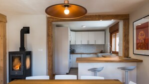 Una cocina moderna con armarios blancos, una isla central y una estufa a leña.