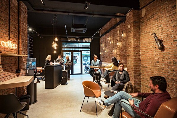 A coffee shop interior with brick walls, hanging lights, and people sitting at tables.