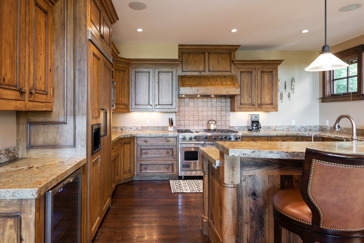 A kitchen with wooden cabinets, a large island, stainless steel appliances, and a pendant light.