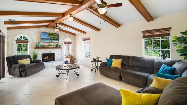 A spacious living room with a fireplace, a large sofa set, and a ceiling fan. - Spacious pool home in Wellington near WEF (Wellington)