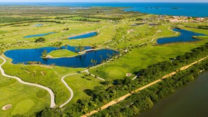 An aerial view of a golf course with multiple ponds, a clubhouse, and a residential area in the background. - Private Patio Retreat with Zen Vibe and Laundry (Ponce)