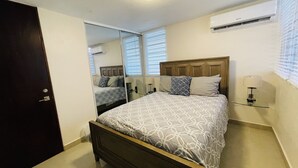 A bedroom with a bed, a bedside table with a lamp, a mirror, and an air conditioning unit. - Private Patio Retreat with Zen Vibe and Laundry (Ponce)